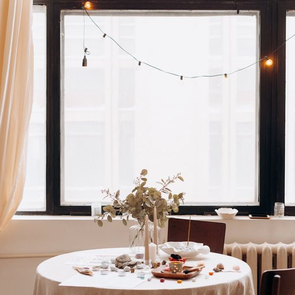 Woman sitting in a lotus yoga pose, looking serene and balanced in a bright room.